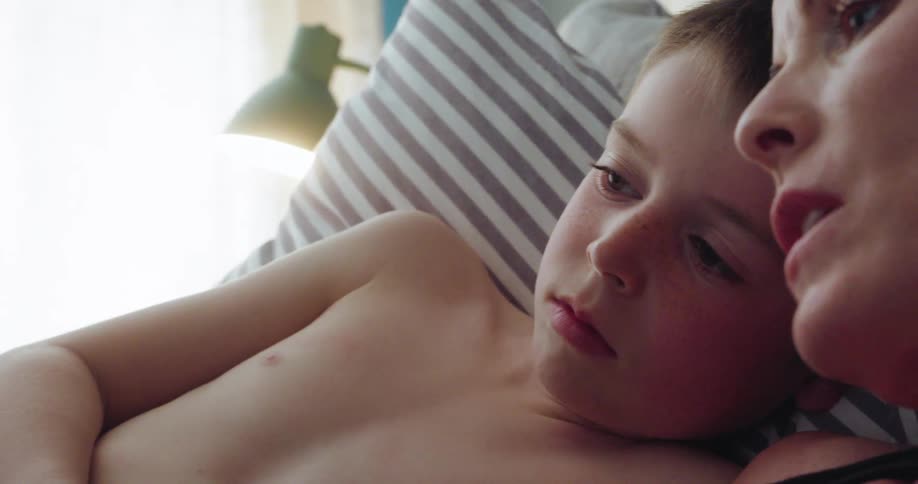 The mother is talking with her son in bed