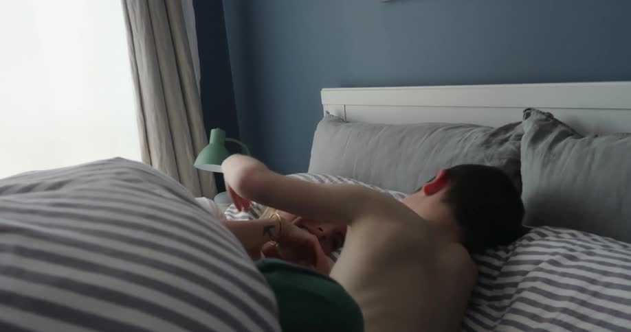 Mother and son laugh and smile while lying on a bed during the daytime