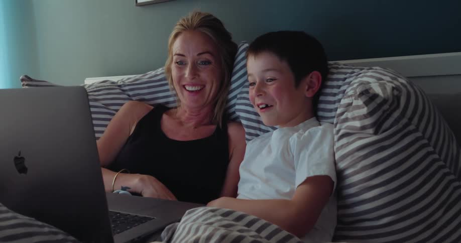 A mother and son laugh at the laptop together