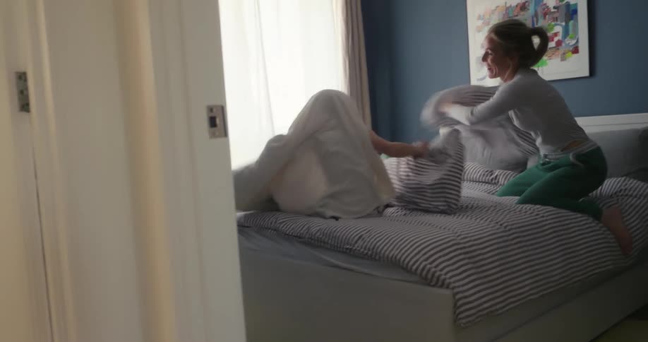 Mother and son having a pillow fight in the childrens bedroom