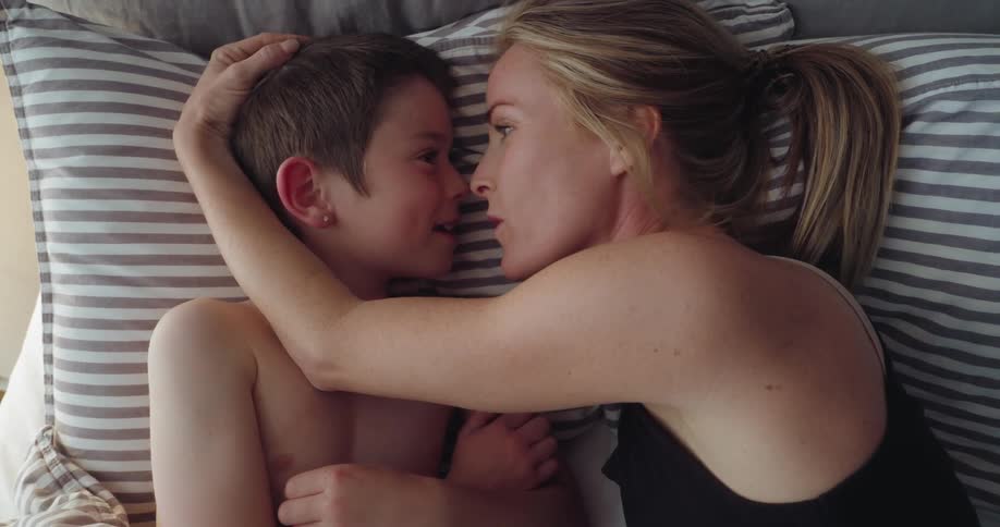 A mother talks with her son in bed