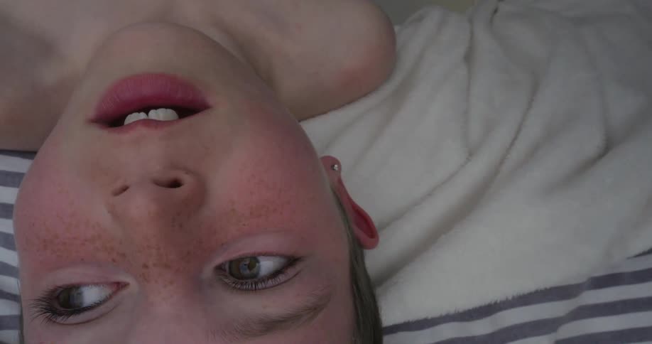 Child leaning over edge of bed