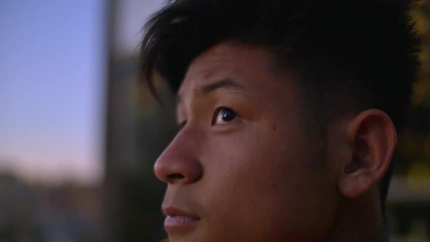 An asian man stares out at the sky