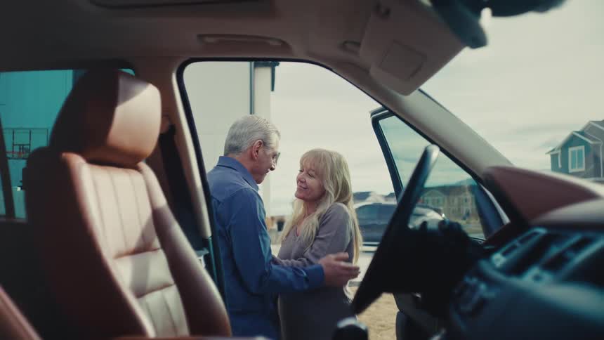 Husband kissing his wife goodbye as he climbs into vehicle