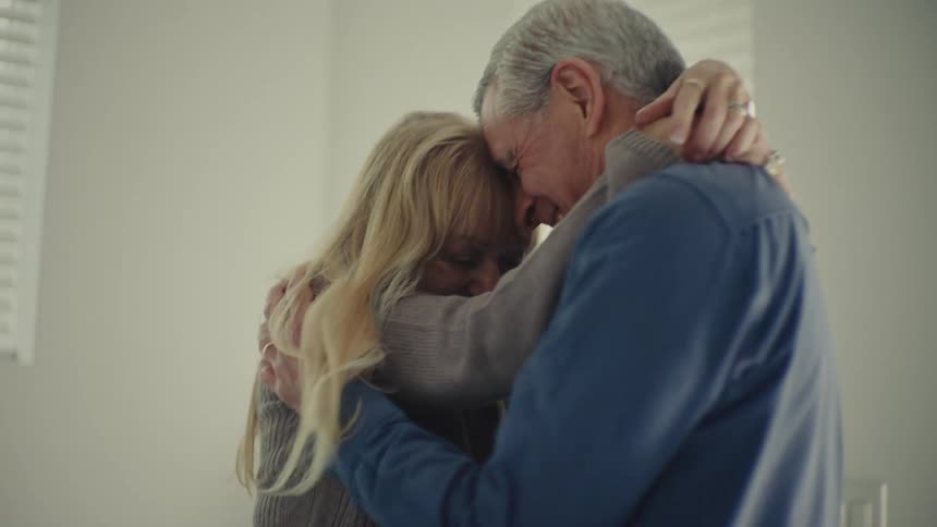 An older man and woman share an intimate joyful embrace touching foreheads as they smile warmly at each other