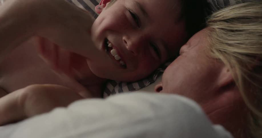 Mother and son happy and laughing while laying in bed