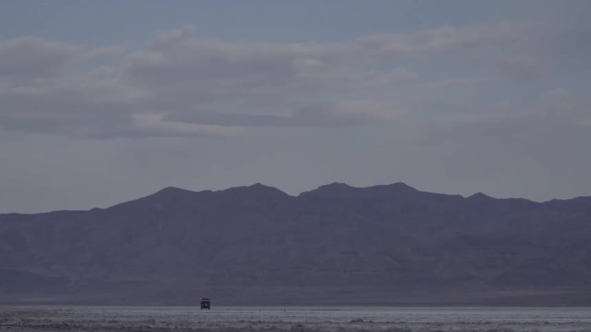 One vehicle drives in an isolated area towards a mountain
