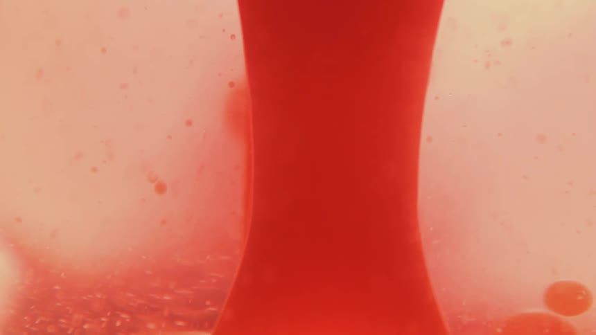 Red bubbles float to the surface in clear liquid