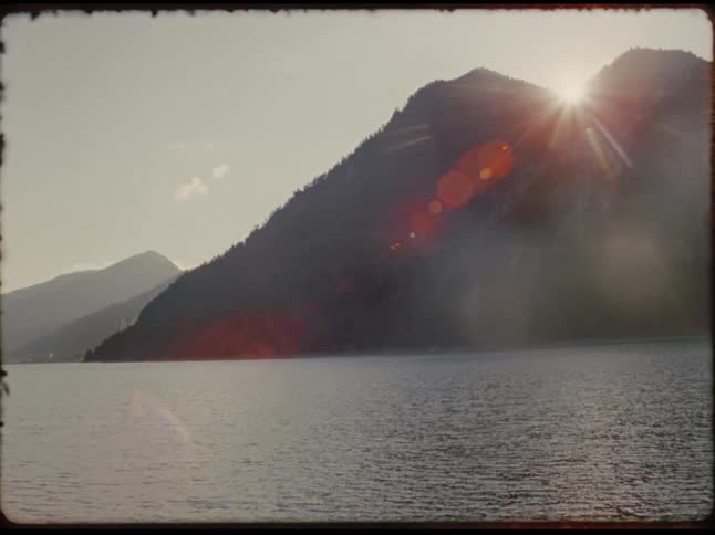 Sun shines brightly between mountains along the coast