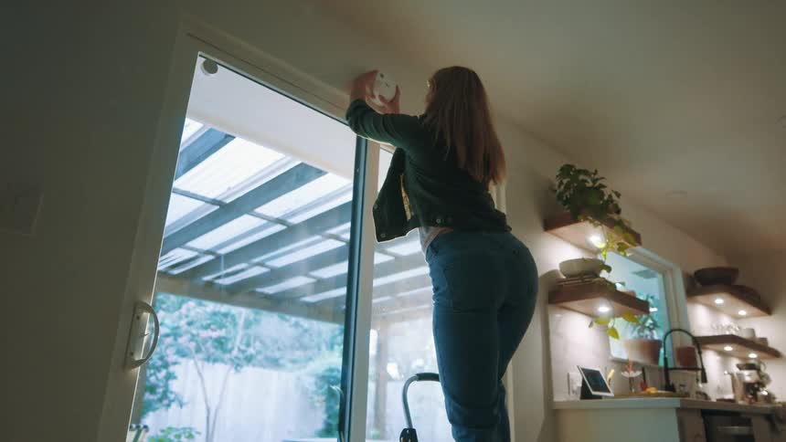A footage of a lady fixing a device indoor