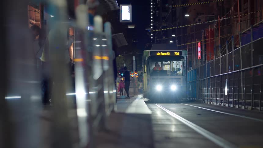 A subway train arriving at the station with people standing nearby waiting for it