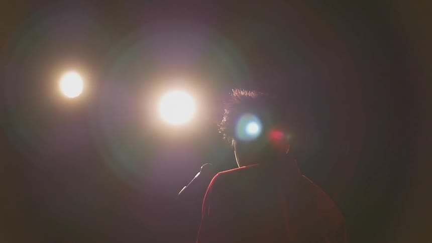 A man stands in front of lights on a stage