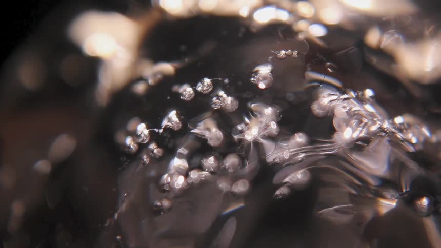 Bubbles cover a shiny black surface