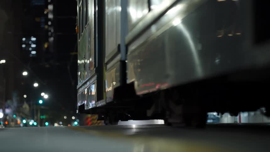 A tram travels through a lit city street at night