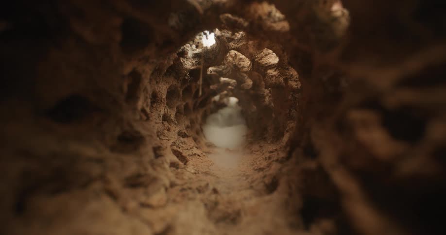 A closeup view through a rocky tunnel with white smoke rising creating an eerie abstract feel