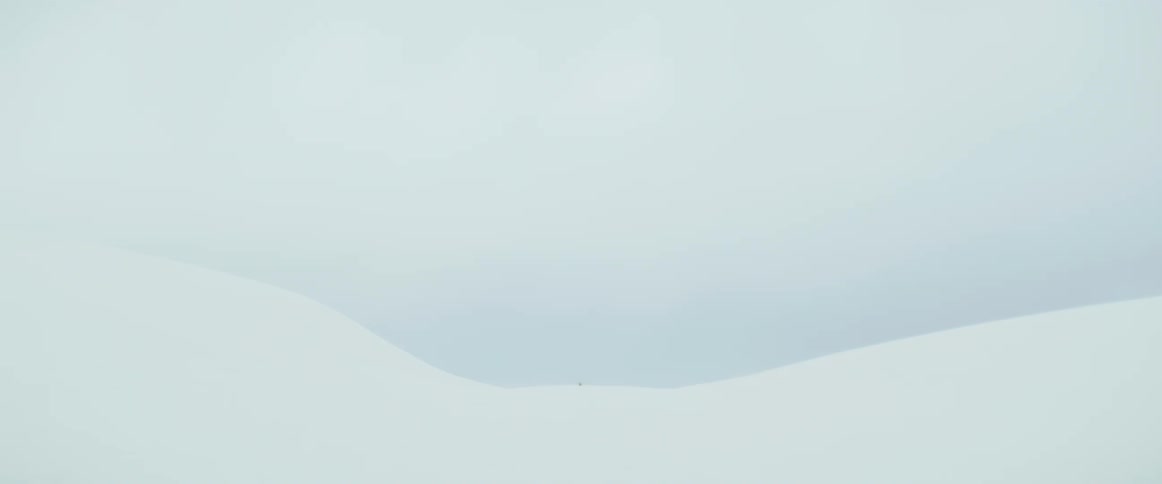 A snowcovered mountain under a white and cloudy sky