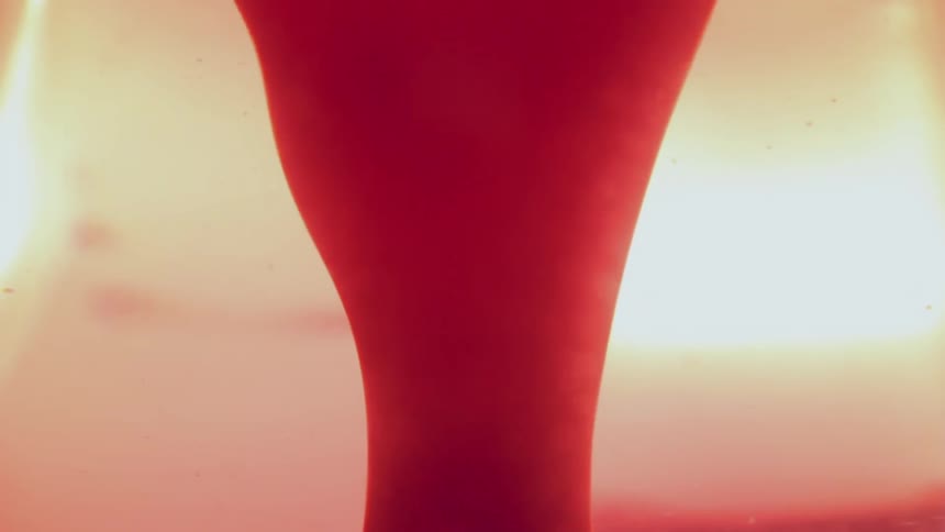 A red waxy liquid flows in a suspension