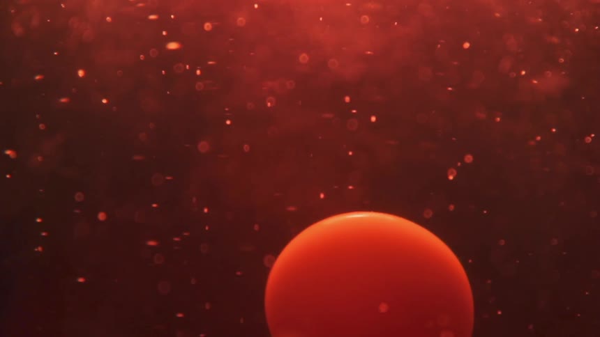 A drop of orange liquid passes through red liquid