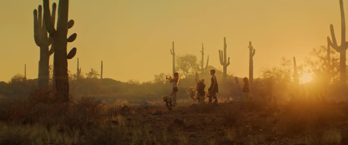 Children walk through the desert shooting slingshots