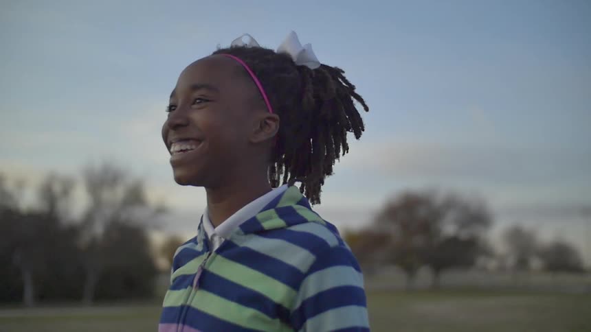 A child smiles as they walk on the field