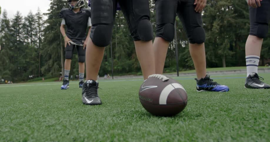 Football players get out of a huddle and move towards the football