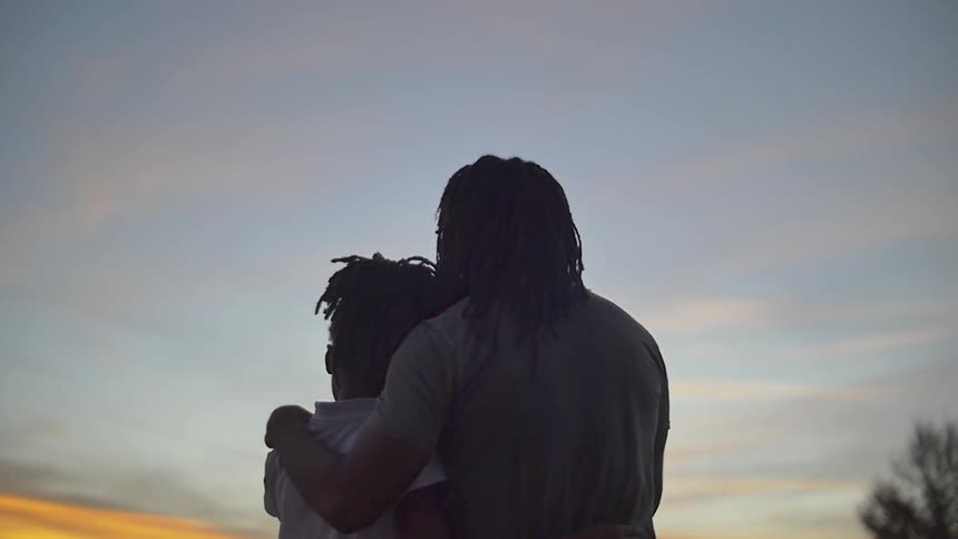 A man and woman stand together watching the sunset