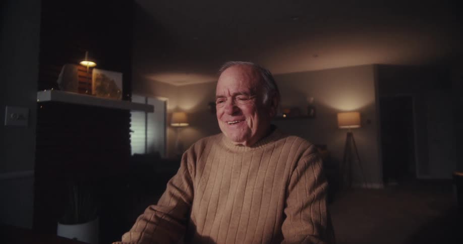 A man laughs and smiles at his laptop