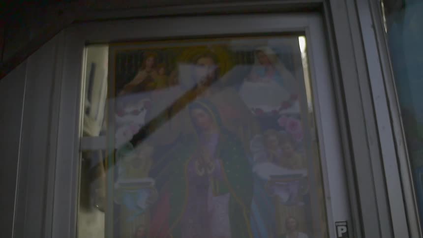 A virgin mary poster hangs in a storefront