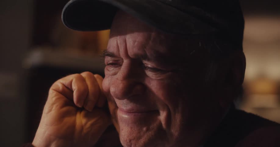 A man leans his chin on his hand and smiles