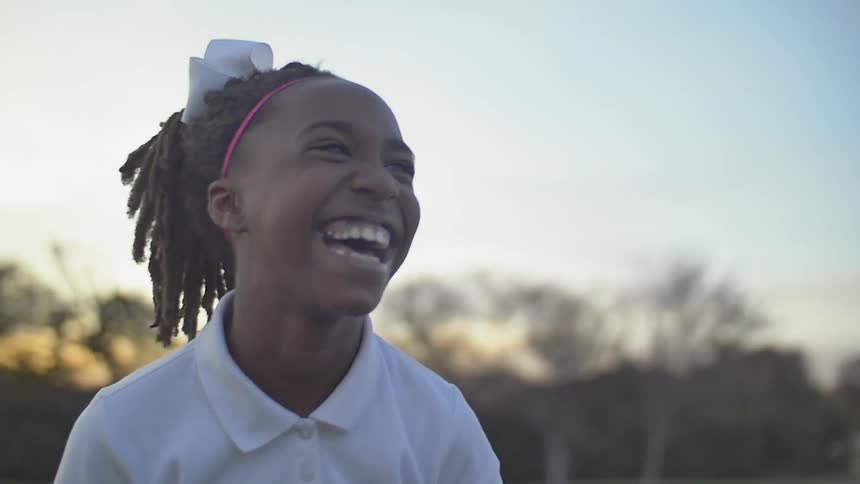 A child laughing at something in the yard