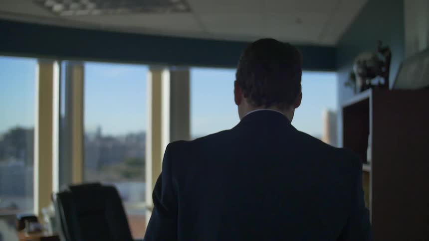 A man walks towards a window in an office
