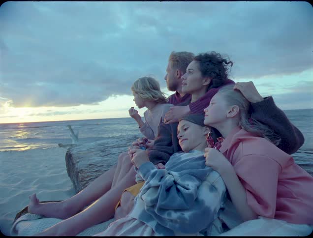 A family sit together on the sand