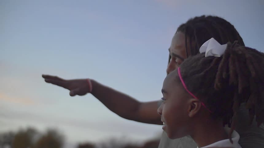 A man points out the sunset with a girl