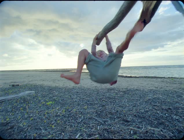 Two children are playing around and running on the shore of a beach