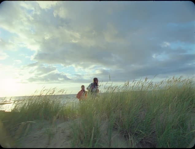 Children run through the reeds on the beach
