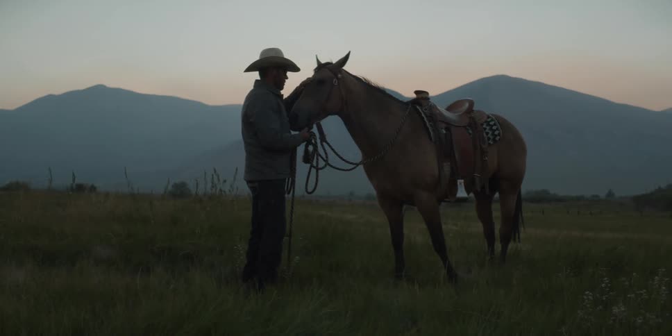 The cowboy pets his horse on the prairie