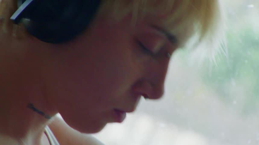 A woman listens to music by the window