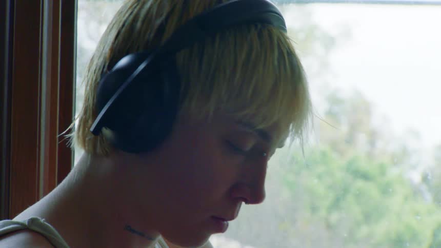 A woman nods her head while listening to music