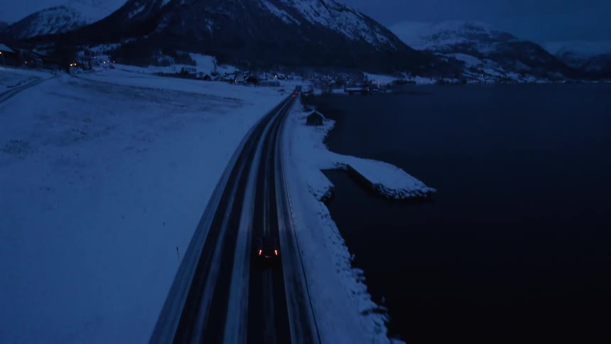 Twoway road on the edge of a lake with snowy mountains around