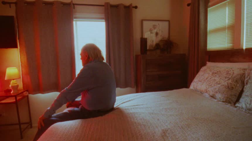 A man sits in bed watching television