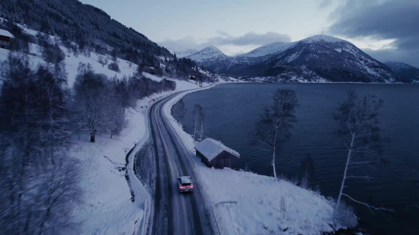An suv travels on a lakeside highway on a snowy winter day