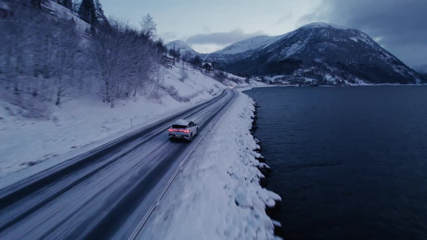 The car drives on the road along the lake