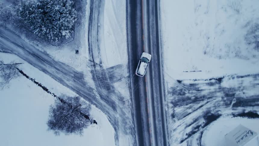 A car makes a turn on the snow filled street