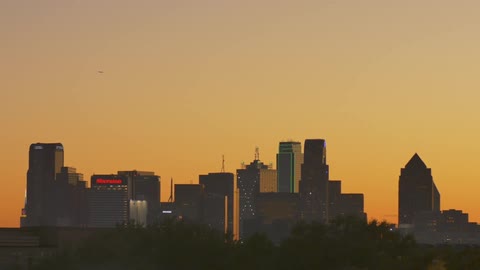 City skyscrapers stand in the distance at sunset