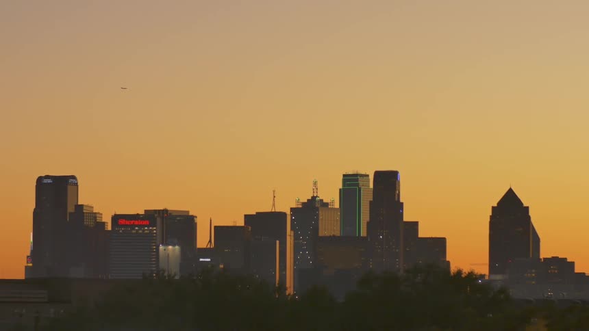 City skyscrapers stand in the distance at sunset