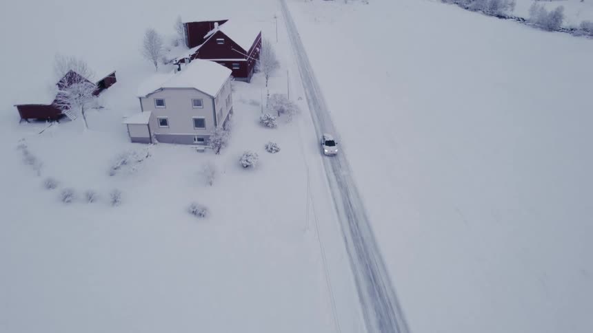 The small town is covered in snow as the car drives by