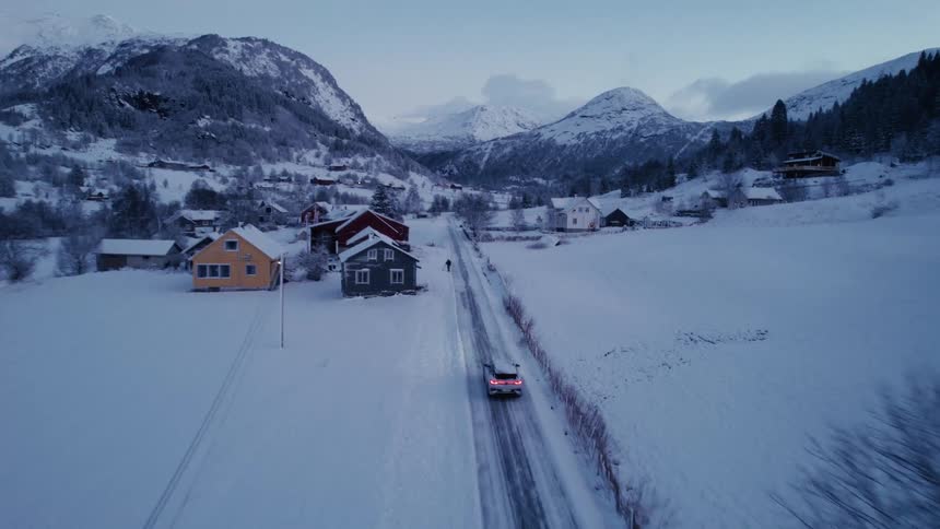 The car drives on the snow covered road towards the mountains