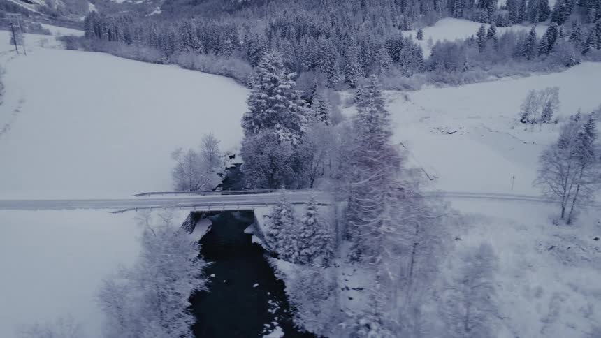 A car drives on the snow covered road over a bridge