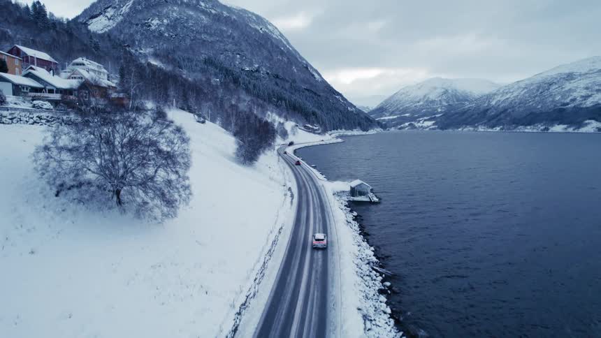 Cars drive by the lake near the mountains