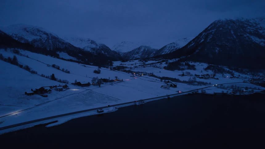 Night flight over a coastal village and a freeway by the sea